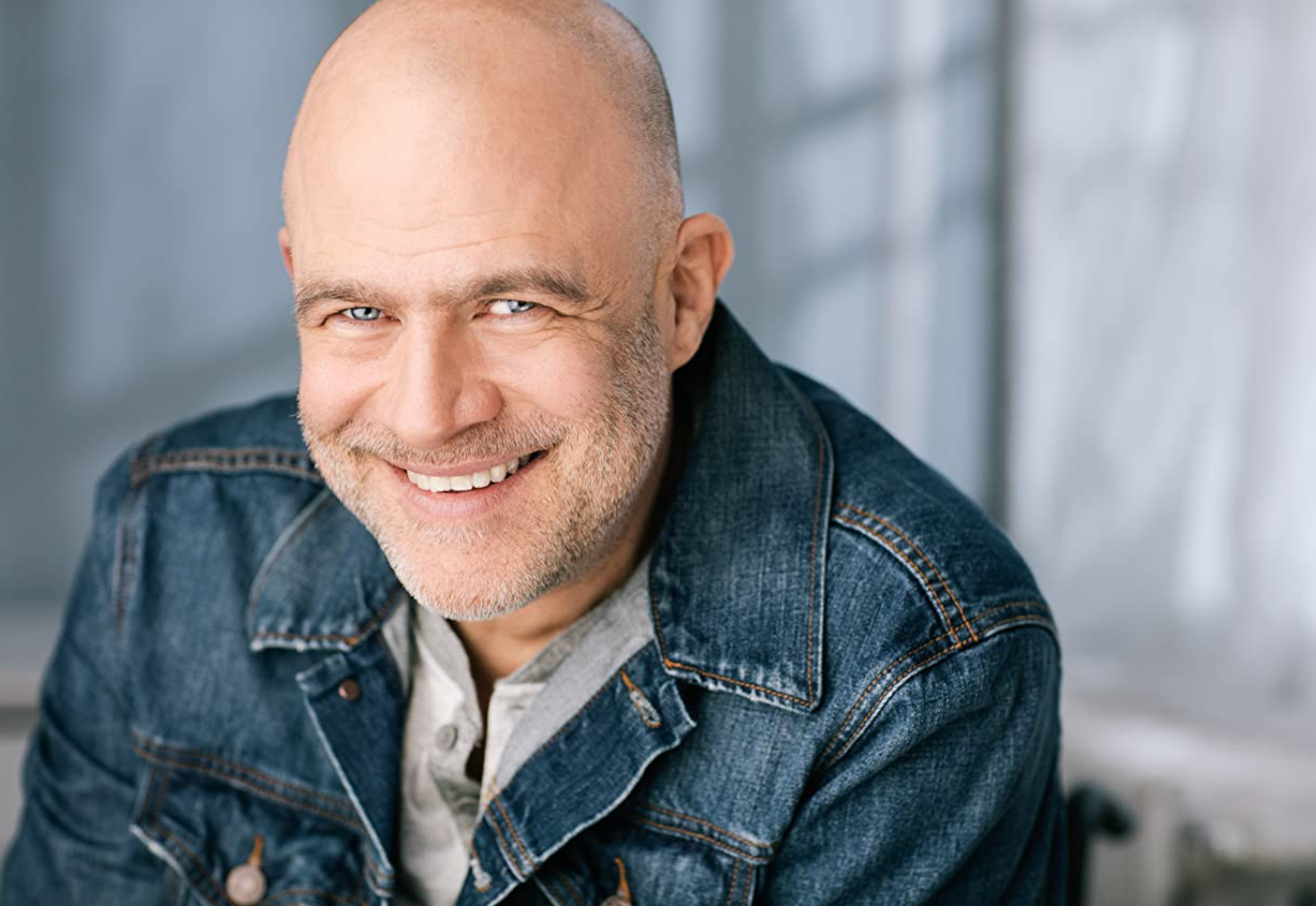 head shot of a smiling middle aged man dressed in a blue jean jacket