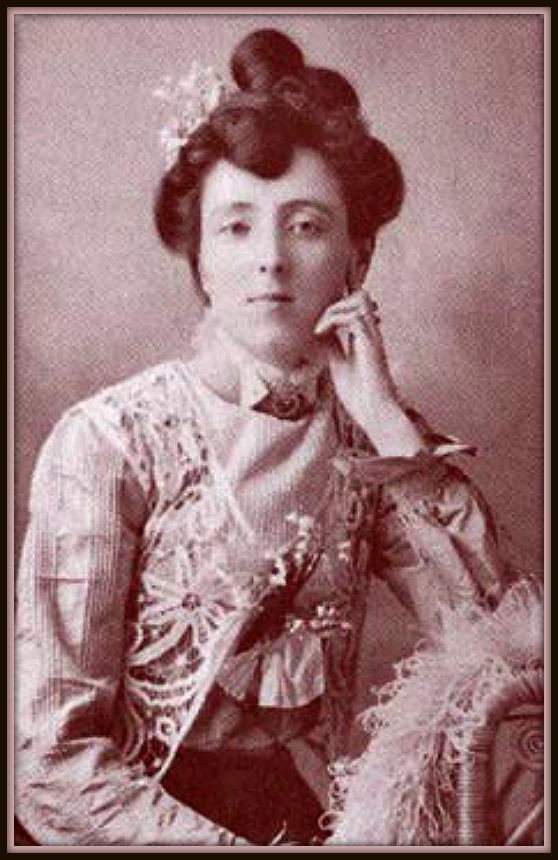 Sepia coloured picture of a seated woman with one hand resting on her chin. She is wearing a blouse embroidered with flowers. She is starring directly at the camera.